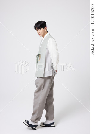 A young man wearing a hanbok and walking with his back behind him. 121016200