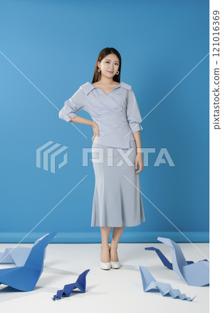 Portrait of a woman standing and posing in front of a blue snake folded out of paper Portrait of a woman standing and posing in front of a blue snake folded out of paper 121016369