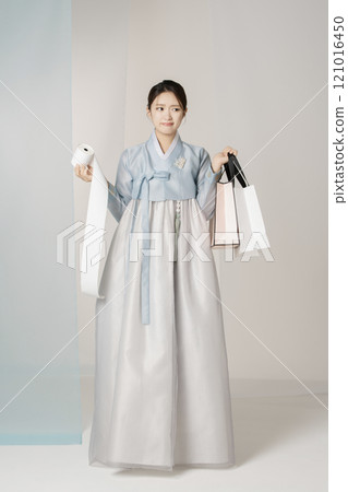 A beautiful woman standing wearing an elegant and elegant hanbok, holding a shopping bag and a receipt stretched out like a roll of toilet paper. 121016450