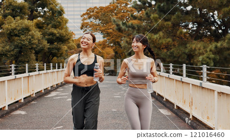 Running, fitness and exercise for women, bridge and routine in morning, smile and bonding with conversation. Outdoor, workout and Asian people with bottle of water, happy and wellness for friends 121016460