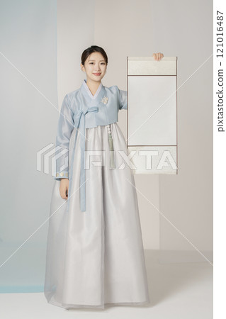 A beautiful woman wearing an elegant Hanbok and holding a traditional scroll scroll. 121016487