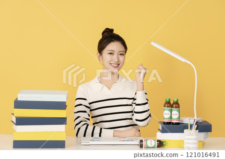 A woman posing in front of a stack of books and a laptop stand A woman posing in front of a stack of books and a laptop stand 121016491