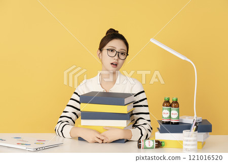 A college student sighing while holding a pile of books A college student sighing while holding a pile of books 121016520