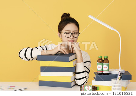 A college student thinking while holding a pile of books A college student thinking while holding a pile of books 121016521