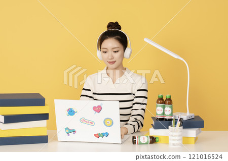 Image of a college student wearing a headset, opening a laptop, and studying Image of a college student wearing a headset, opening a laptop, and studying 121016524