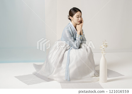 A beautiful woman wearing a luxurious and elegant hanbok sitting next to a vase A beautiful woman wearing a luxurious and elegant hanbok sitting next to a vase 121016559