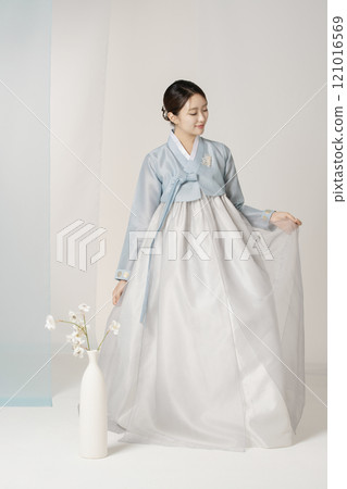 Beautiful woman wearing luxurious and elegant hanbok standing next to a vase 121016569