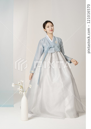 Beautiful woman wearing luxurious and elegant hanbok standing next to a vase Beautiful woman wearing luxurious and elegant hanbok standing next to a vase 121016570