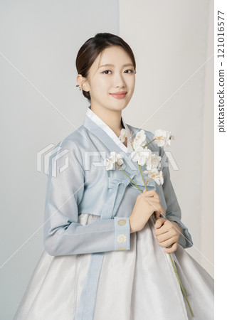 A beautiful woman wearing a luxurious and elegant hanbok is standing holding a flower A beautiful woman wearing a luxurious and elegant hanbok is standing holding a flower 121016577