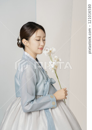 A beautiful woman wearing a luxurious and elegant hanbok is standing holding a flower A beautiful woman wearing a luxurious and elegant hanbok is standing holding a flower 121016580