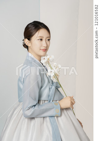 A beautiful woman wearing a luxurious and elegant hanbok is standing holding a flower A beautiful woman wearing a luxurious and elegant hanbok is standing holding a flower 121016582