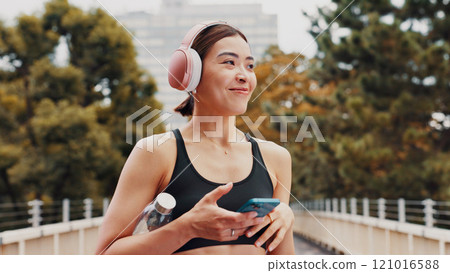 Thinking, woman and headphones with fitness in city, listening to music and sports podcast. Female athlete, phone and streaming radio with exercise routine, training website and break on Japan bridge 121016588