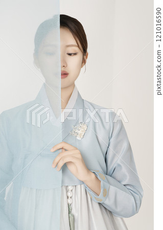 A beautiful woman wearing a luxurious and elegant Hanbok, standing behind a blue cloth A beautiful woman wearing a luxurious and elegant Hanbok, standing behind a blue cloth 121016590