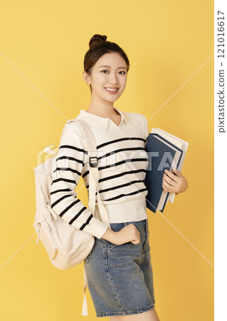 A college student wearing casual clothes and posing with a book 121016617
