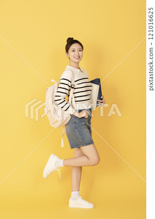 A college student wearing casual clothes and posing with a book 121016625