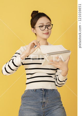 A college student wearing casual clothes and holding a pencil and notebook 121016651