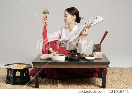 A young shaman sitting with a shamanic bell and a fan in front of a table with shamanic tools spread out. 121016741