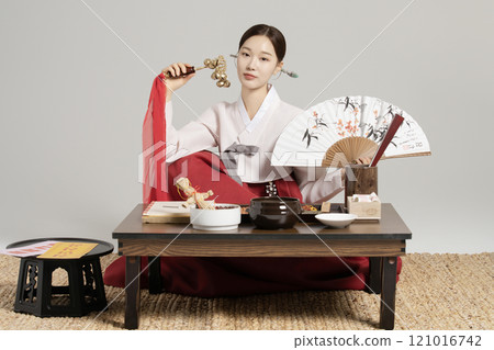 A young shaman sitting with a shamanic bell and a fan in front of a table with shamanic tools spread out. 121016742