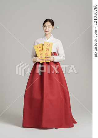 A woman in her 20s wearing a hanbok, wearing a colorful hairpin, and posing while holding an amulet. A woman in her 20s wearing a hanbok, wearing a colorful hairpin, and posing while holding an amulet. 121016766