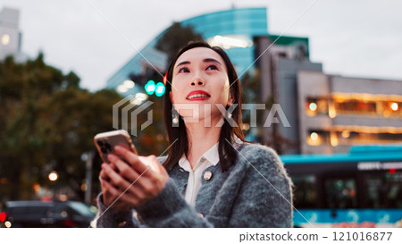Thinking, mobile and woman in city for travel, text or message on app in Japan. Planning, phone and Asian person outdoor for dream vacation, future vision and ideas for blog on internet at night 121016877