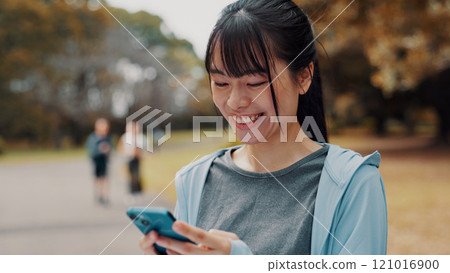 Smile, woman and typing with phone of fitness outdoor, communication and research of exercise application. Happy, athlete and mobile for gym membership, training schedule and workout routine in Japan Smile, woman and typing with phone of fitness outdoor, communication and research of exercise application. Happy, athlete and mobile for gym membership, training schedule and workout routine in Japan 121016900