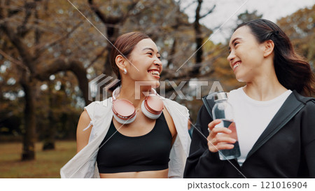 Fitness, friends and Japanese women in nature with workout, break and body health for wellness. Exercise, smile and happy girls talk at park for sports chat, walking or laugh at funny joke to relax 121016904