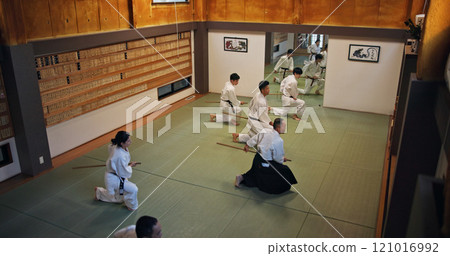 Dojo, class and Aikido exercise group in gym with wood sword Japanese martial arts and fight in wellness studio. Learning, sport and bamboo weapon with people and strike practice for defence above 121016992