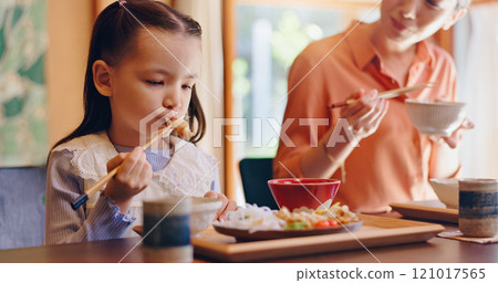Mom, girl and chopsticks with eating, home or teaching for food, lunch or bonding with love in dining room. People, mother and daughter family house for meal, diet or nutrition with learning in Japan 121017565