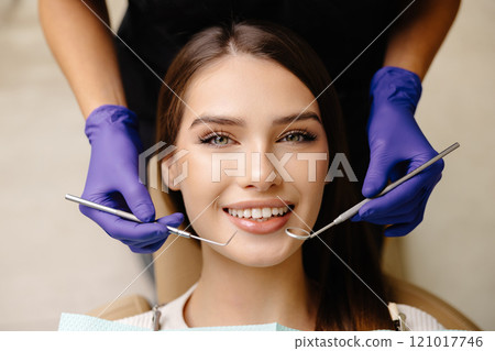 Happy patient during a visit to the dentist. The doctor is checking teeth using a dental instrument, ensuring proper oral care in the dentistry clinic 121017746