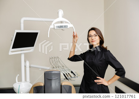 Portrait of young female dentist in modern clinic. A female dentist kindly invites you to an appointment Portrait of young female dentist in modern clinic. A female dentist kindly invites you to an appointment 121017761