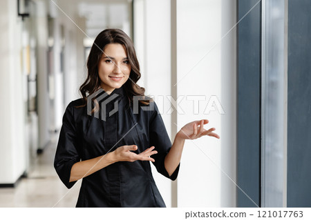 Young female doctor is standing in a hospital hall and looking at the camera 121017763