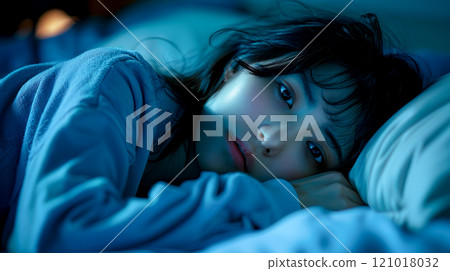 一個年輕女子躺在黑暗房間的床上思考 121018032