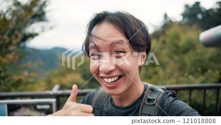 Man, thumbs up and outdoor in portrait for selfie, fitness update and follower interaction on Mount Takao. Japanese influencer, like emoji or smile on bridge for travel, hiking or social media stream Man, thumbs up and outdoor in portrait for selfie, fitness update and follower interaction on Mount Takao. Japanese influencer, like emoji or smile on bridge for travel, hiking or social media stream 121018808