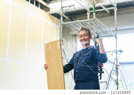 一名木匠在建築工地拿著木材時用拳頭打泵 一名木匠在建築工地拿著木材時用拳頭打泵 121018895