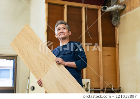 Carpenter holding timber at a construction site 121018897