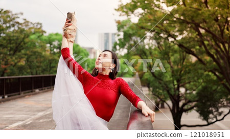 Woman, exercise and ballet stretching in nature, outdoor and practice performance in park. Female person, professional dancer and creative talent in Japan, rehearsal and urban garden for elegant art 121018951