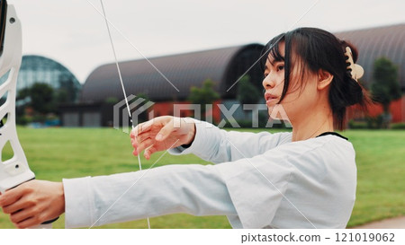 Woman, archery and serious at field with sport for shooting practice and training as athlete in Japan. Tournament, female person and setup recurve bow or equipment for challenge, game or competition Woman, archery and serious at field with sport for shooting practice and training as athlete in Japan. Tournament, female person and setup recurve bow or equipment for challenge, game or competition 121019062