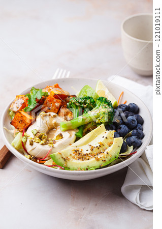 Balanced vegan bowl with baked sweet potato, avocado, berries, salad and hummus. Plant Based Diet Concept. Balanced vegan bowl with baked sweet potato, avocado, berries, salad and hummus. Plant Based Diet Concept. 121019111