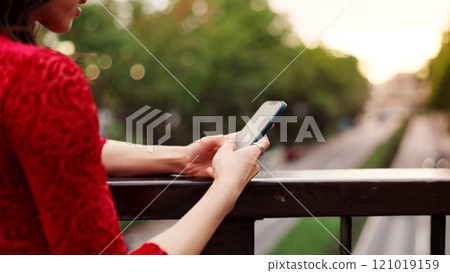 Hands, phone and texting on bridge, nature and outdoor for notification, chat and mobile app by fence in city. Person, smartphone and scroll in town for contact, internet and social network in Japan 121019159