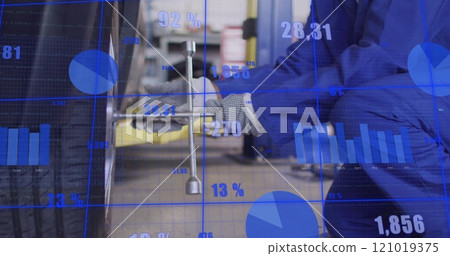 Image of financial data processing over male african american car mechanic fixing tyre 121019375