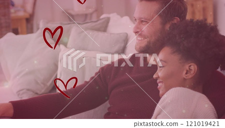 Image of hearts and light spots over diverse couple embracing on sofa and watching tv Image of hearts and light spots over diverse couple embracing on sofa and watching tv 121019421