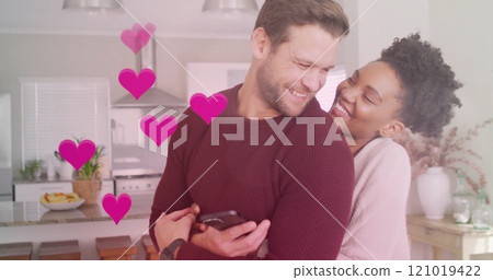 Image of hearts and light spots over diverse couple embracing in kitchen Image of hearts and light spots over diverse couple embracing in kitchen 121019422