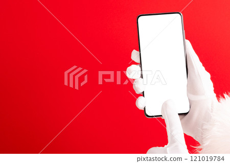 Santa claus hands holding smartphone with copy space on red background 121019784