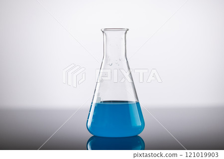 Close up of laboratory beaker with blue liquid and copy space on grey background 121019903