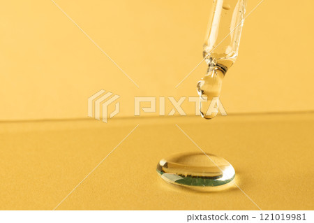 Close up of pipette with drop and copy space on yellow background 121019981