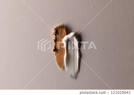 Close up of beauty product white and brown cream smudges with copy space on brown background Close up of beauty product white and brown cream smudges with copy space on brown background 121020041