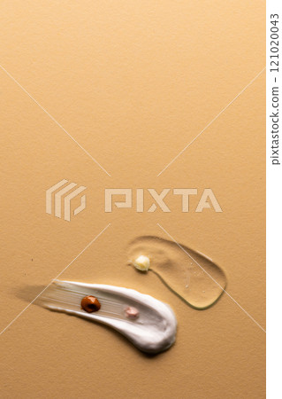Vertical image of beauty product white cream clear serum smudge with copy space on brown background Vertical image of beauty product white cream clear serum smudge with copy space on brown background 121020043