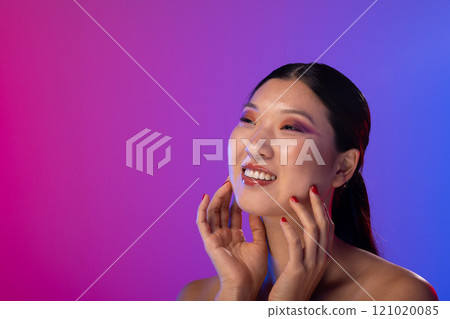 Asian woman wearing purple eye shadow and red nail polish on purple background, copy space 121020085