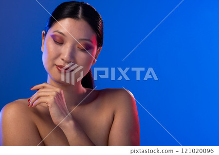 Asian woman wearing purple eye shadow and red nail polish on purple background, copy space Asian woman wearing purple eye shadow and red nail polish on purple background, copy space 121020096