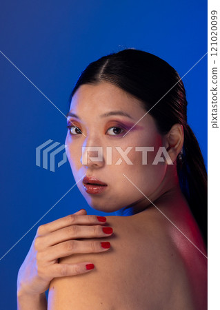 Portrait of asian woman with black hair wearing purple eye shadow on blue background Portrait of asian woman with black hair wearing purple eye shadow on blue background 121020099